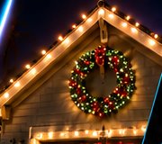 Roof peak outlined in warm white lights with a lit Christmas wreath